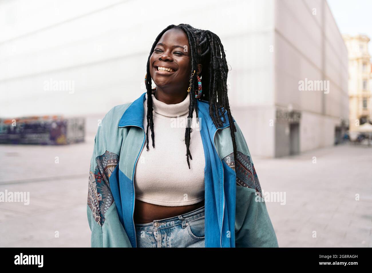 Cheerful african young woman with cool braids smiling and walking in ...