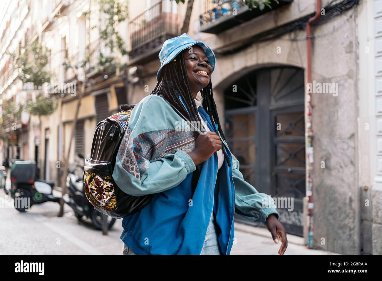 Happy and young african woman with cool braids smiling and walking in ...