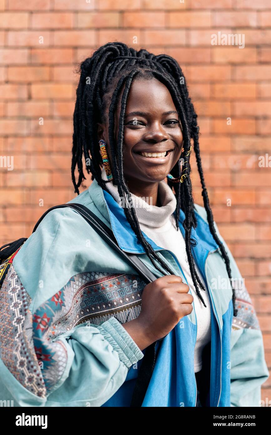 Happy and young african woman with cool braids smiling and looking 