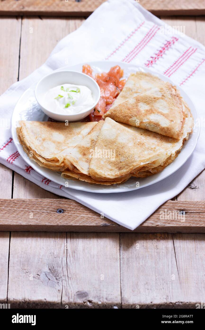 Thin pancakes with salmon and sour cream on a light background. Rustic style. Stock Photo