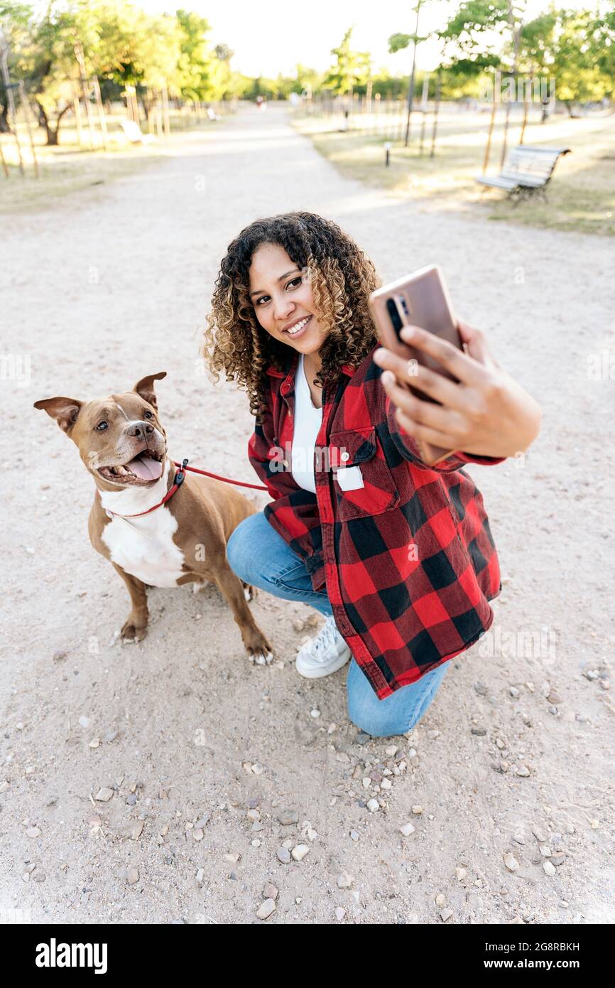Happy woman with curly hair posing with her purebred dog and taking a ...