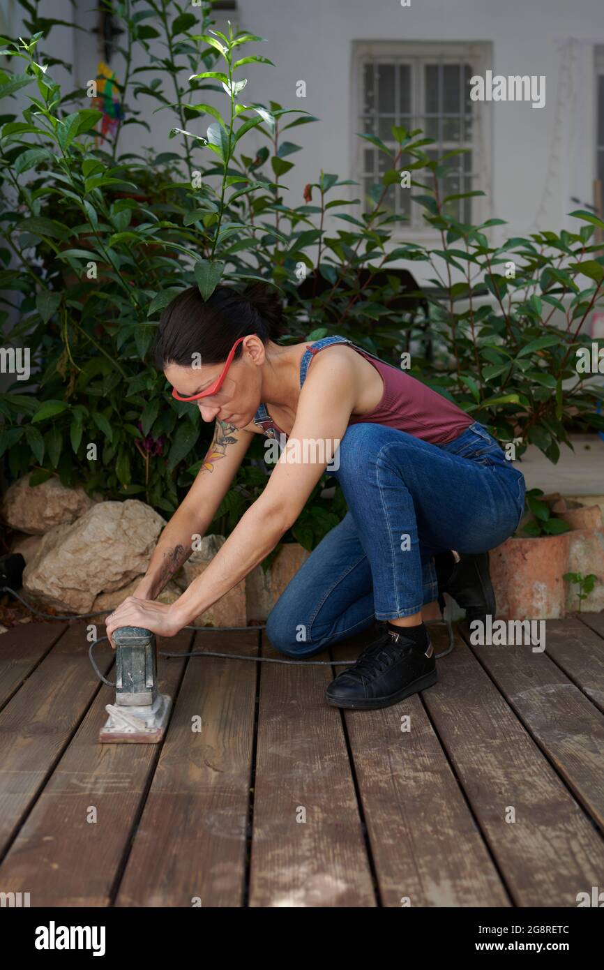 A young woman sanding wood with an electric sander Stock Photo Alamy