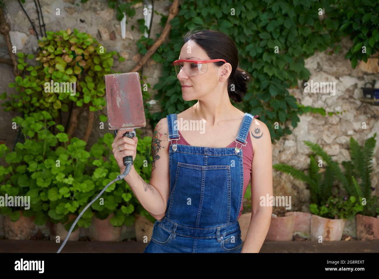 A young woman sanding wood with an electric sander Stock Photo Alamy