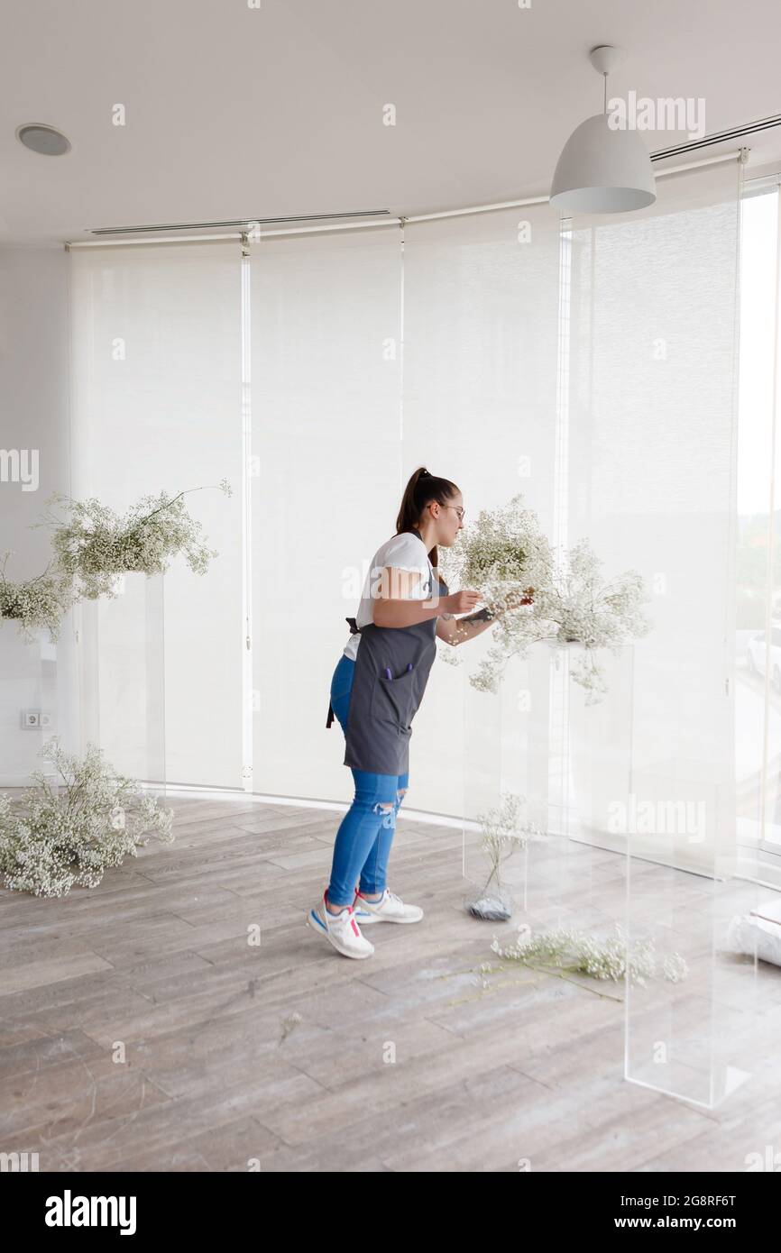 woman florist decorator decorates wedding interior with flowers Stock Photo