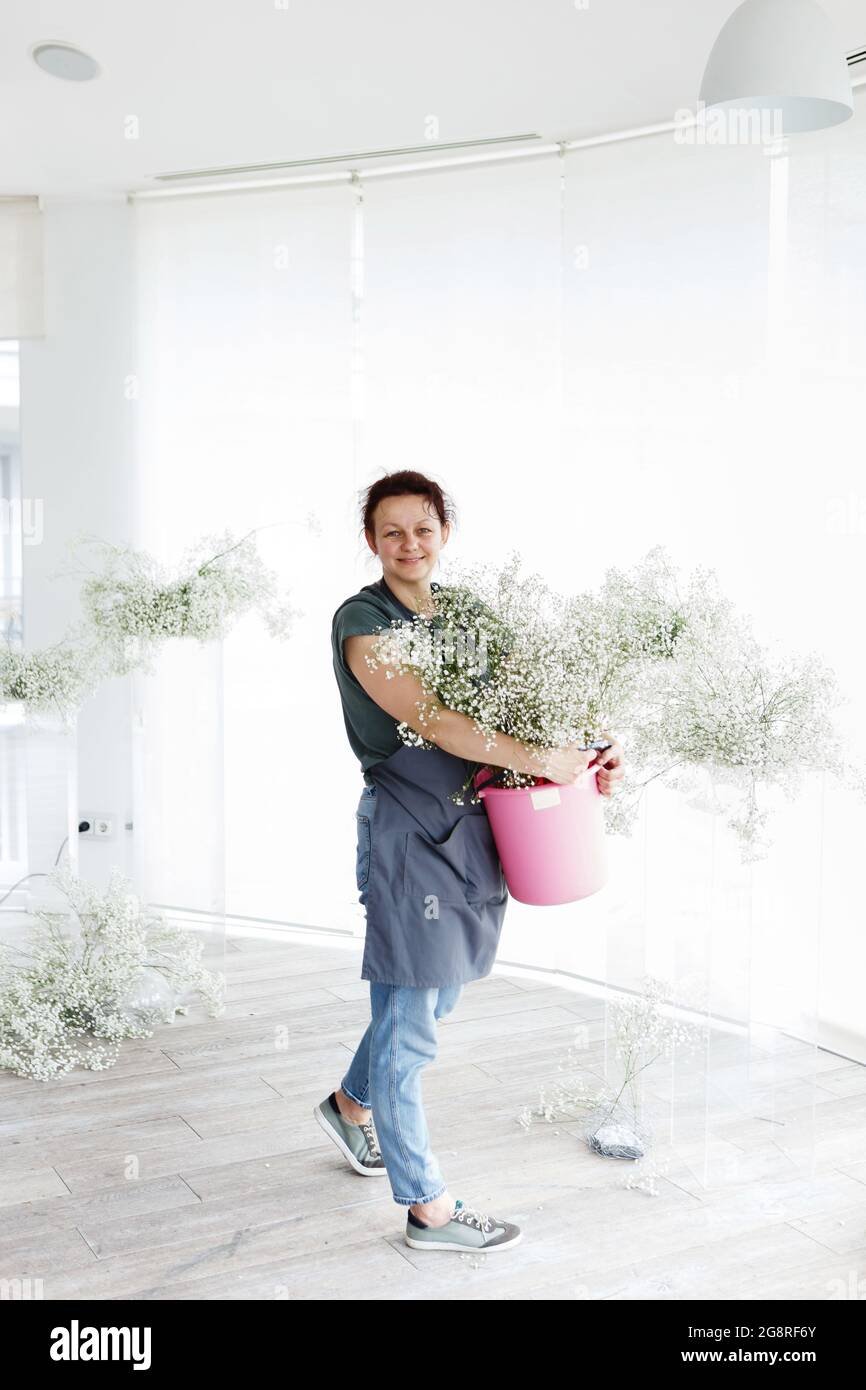 woman florist decorator decorates wedding interior with flowers Stock Photo