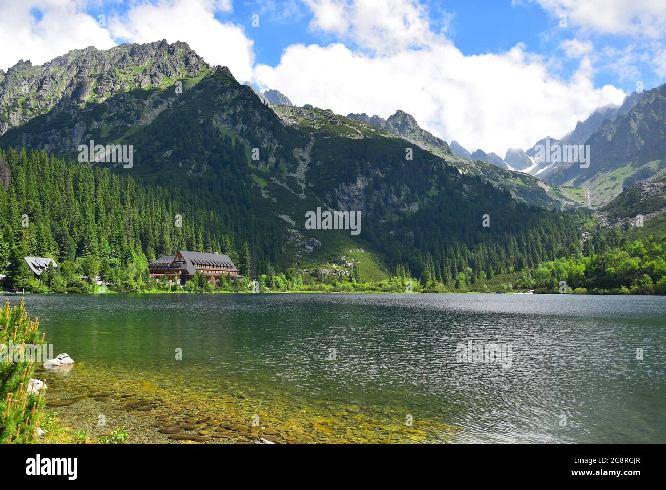 The beautiful lake Popradske pleso, surrounded by the Tatra mountains, and a mountain hotel. Slovakia. Image taken from public ground. Stock Photo