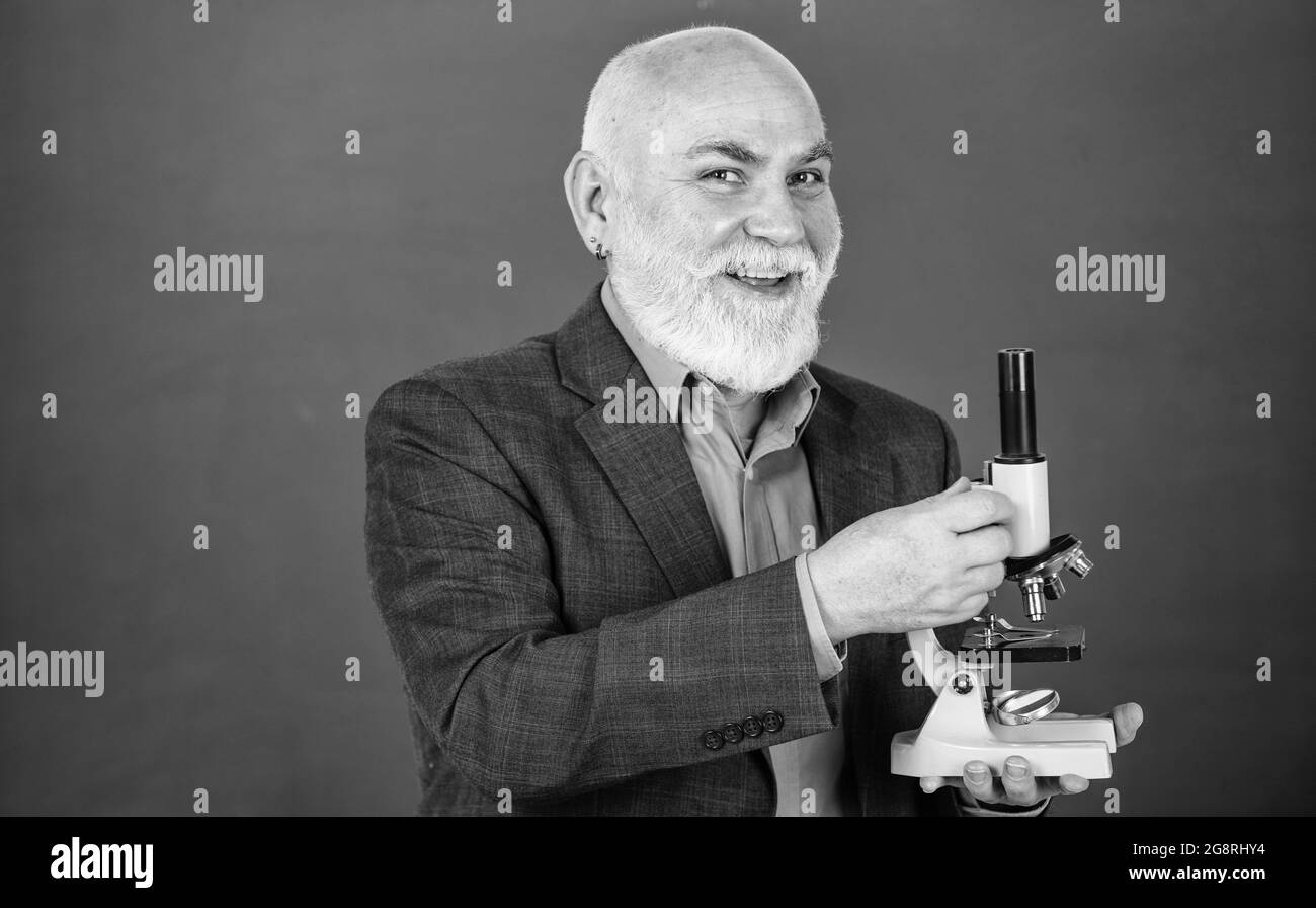 fascinating biology lesson. happy senior teacher use microscope