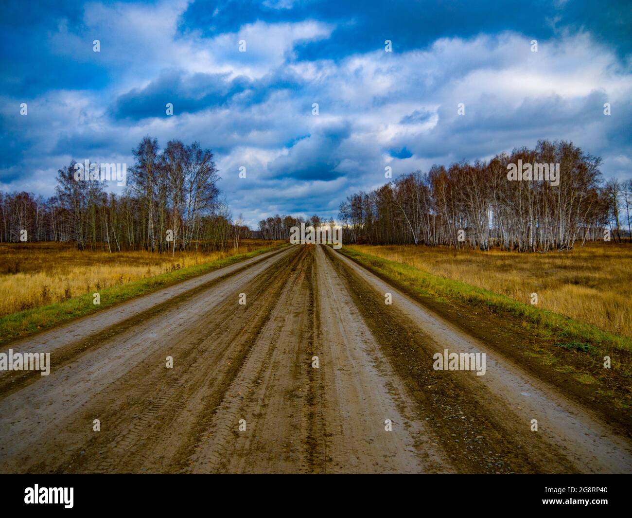 Autumn country road. Clouds over the road. The concept of relax away from civilization. Stock Photo
