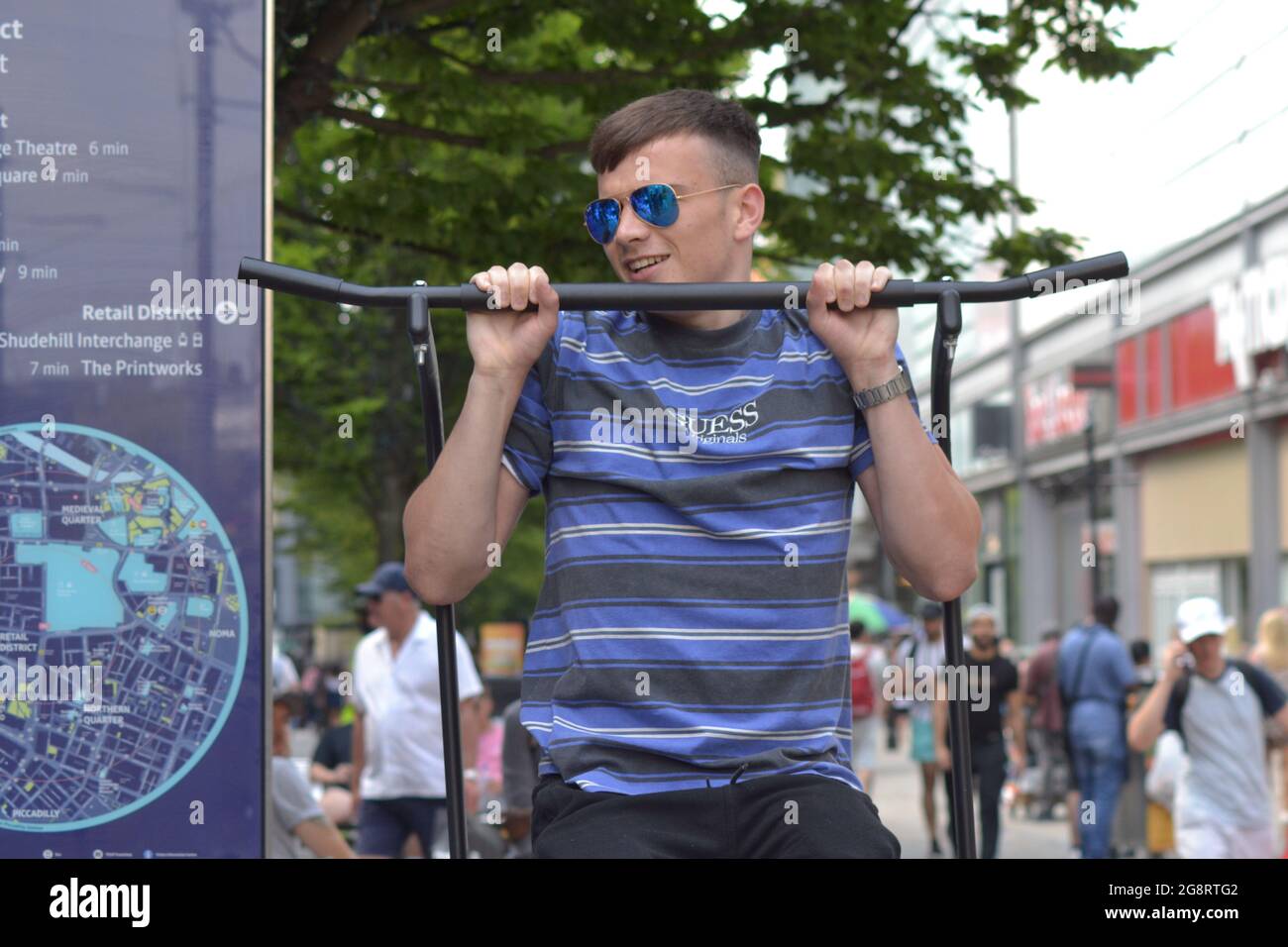 Men Accept A Challenge To Keep Themselves Off The Ground For Two Minutes At A Pull Up And Dip Station Or Pull Up Rack For Gravity Fitness And Weight Training On Market Street
