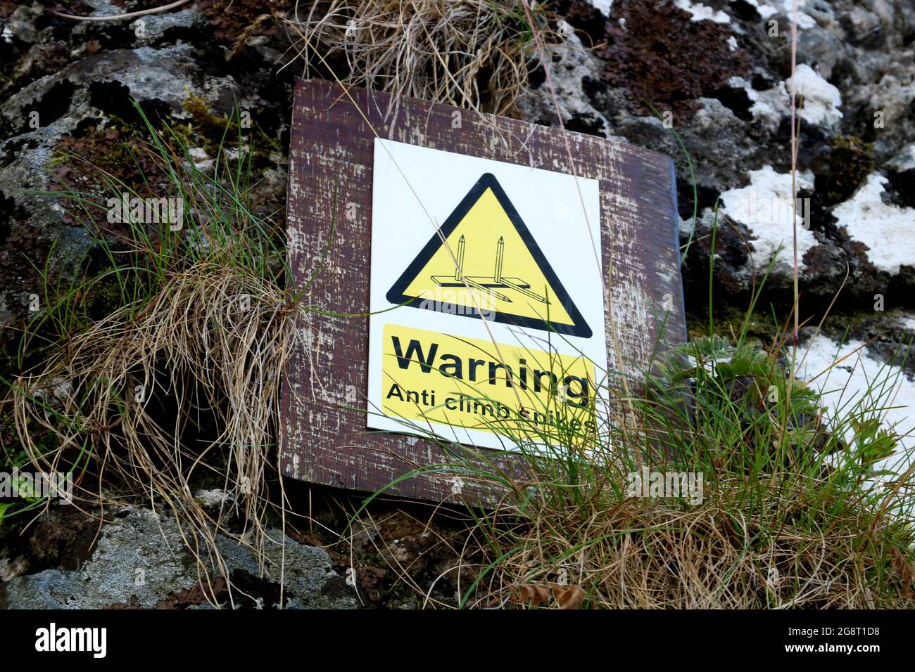 Anti climbing spikes warning sign on an old stone castle wall Stock Photo
