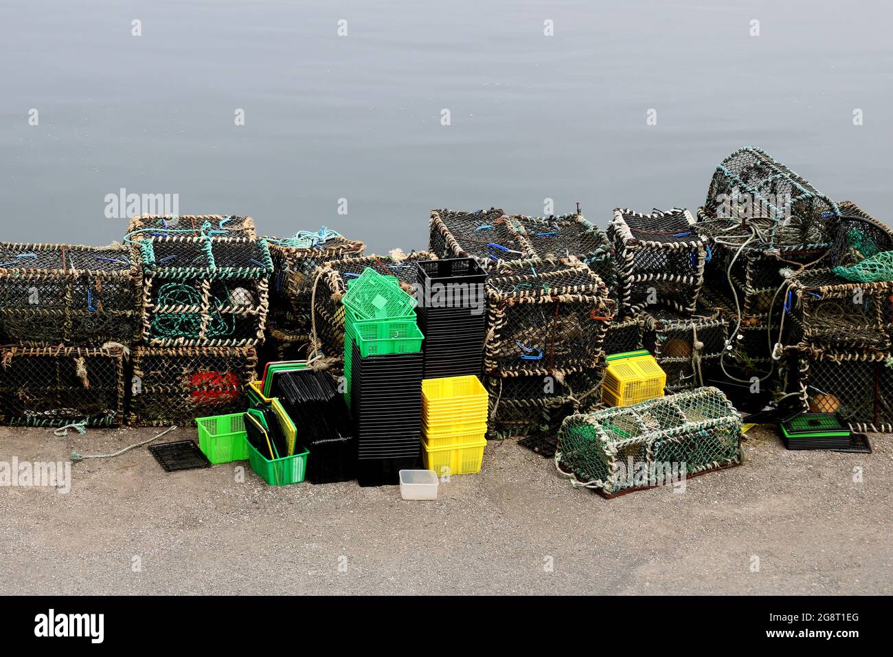 Lobster and crab pots with assorted boxes and tubs at a small coastal harbour Stock Photo