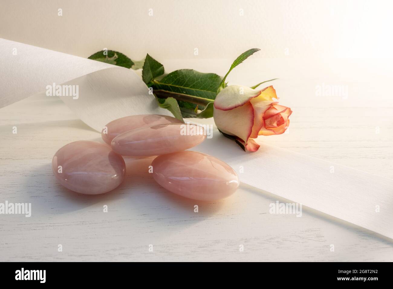 Rose quartz stones for cooling after wax depilation, bandage and a rose flower on a light background, concept for cosmetic treatment, copy space, sele Stock Photo