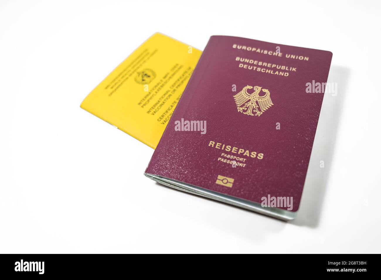 German Passport and yellow International Certificate of Vaccination book isolated on a white background, requirement to travel is a record for SARS-Co Stock Photo