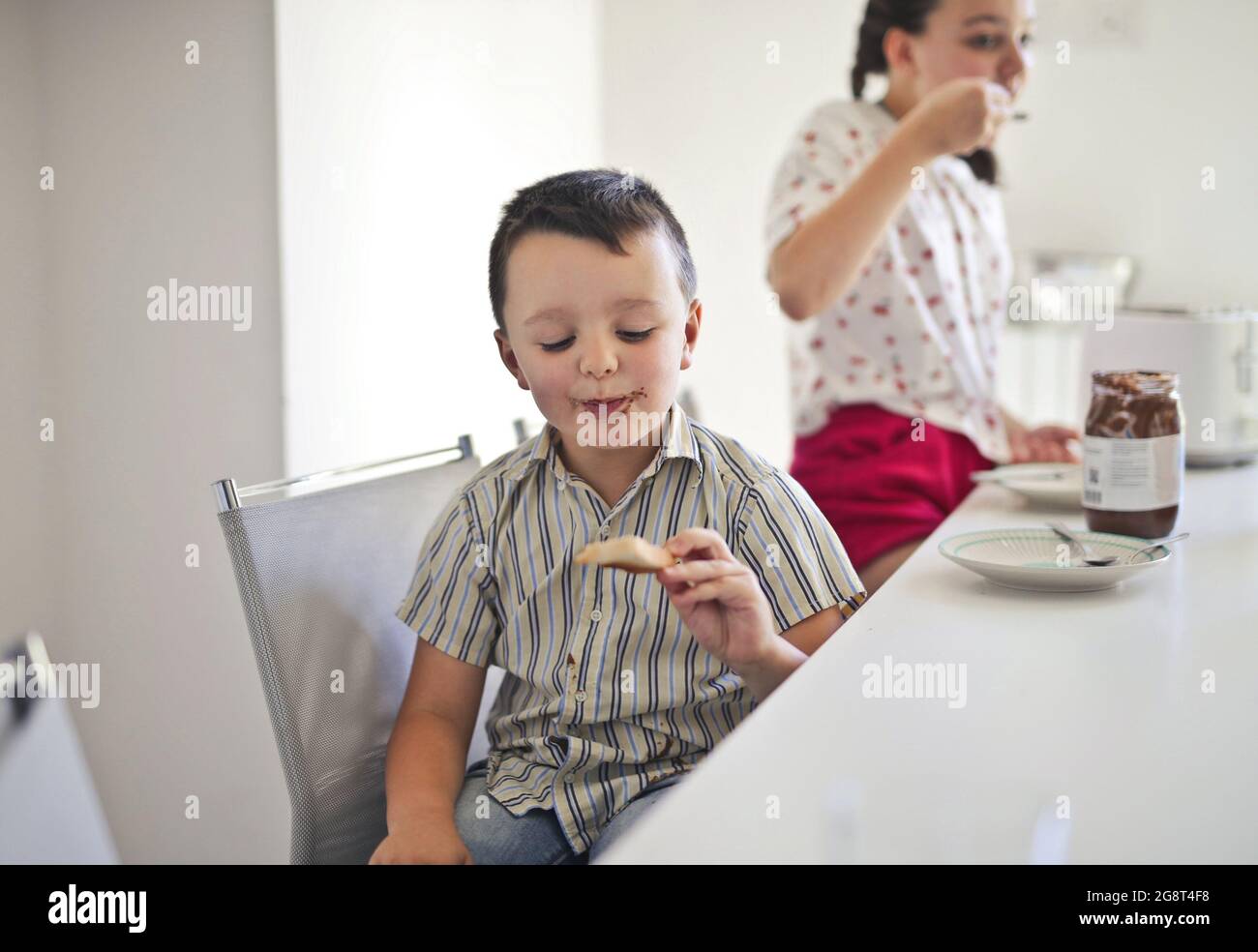 Siblings eating chocolate for breakfast in the kitchen in the morning Stock Photo