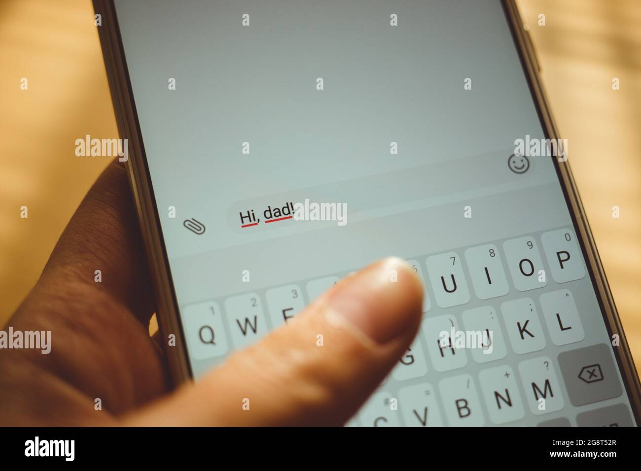 Human hand typing on a white smartphone a message Hi, dad. Stock Photo