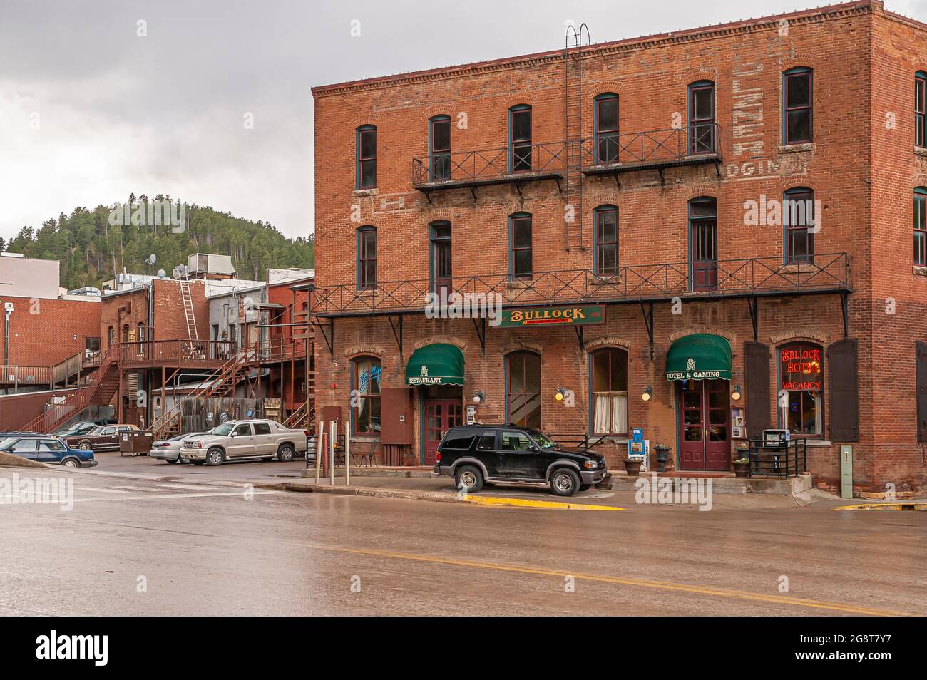 Deadwood SD, USA - May 31, 2008: Downtown Main Street. Red brick historic hotel Bullock back side along CanAm highway under rainy sky with cars parked Stock Photo