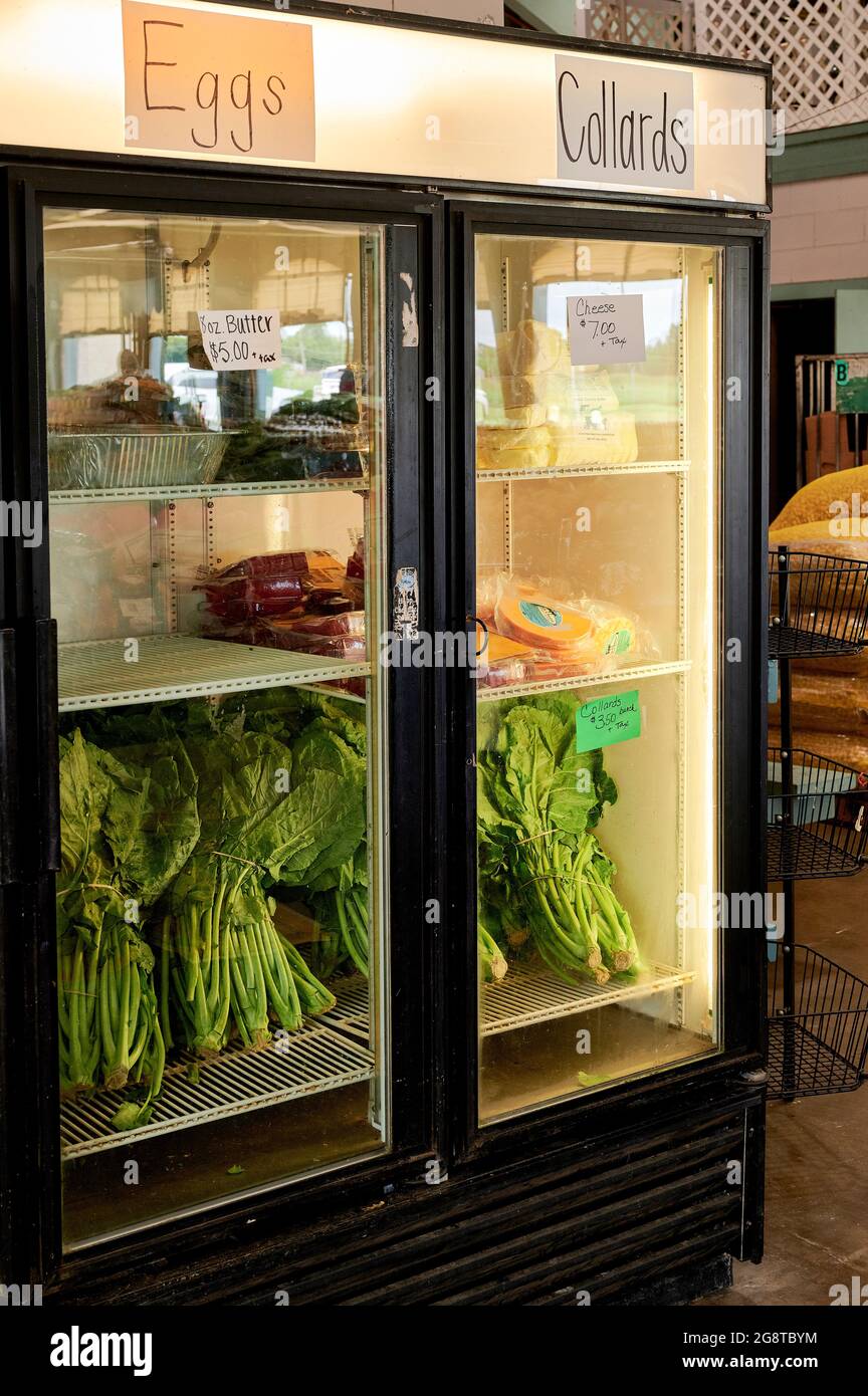 Refer or refrigerator at farm market with collard greens, cheese, butter and eggs on display for sale. Stock Photo