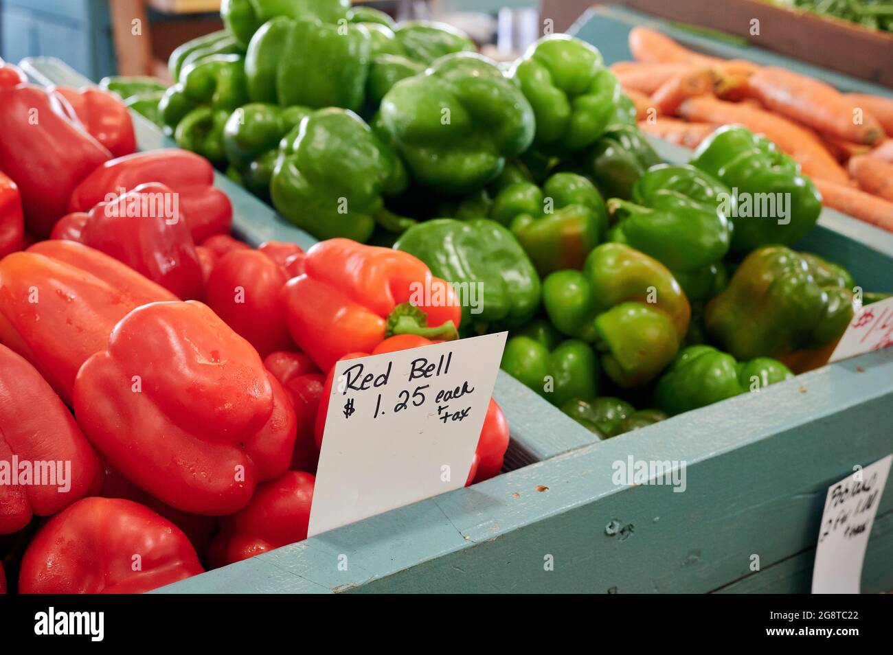 Red and green peppers in a display of fresh vegetables and produce, for sale at a farm or farmers market. Stock Photo
