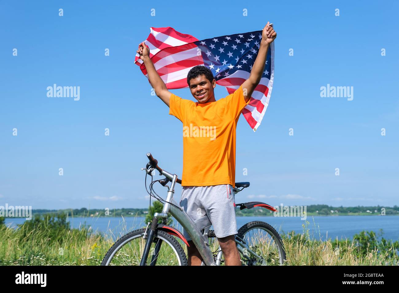 Afro American man holding and waving USA flag and standing with bike Stock Photo