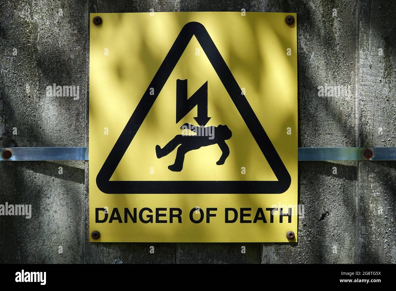 Closeup of 'Danger of Death' by electrocution warning sign mounted on the concrete wall Stock Photo