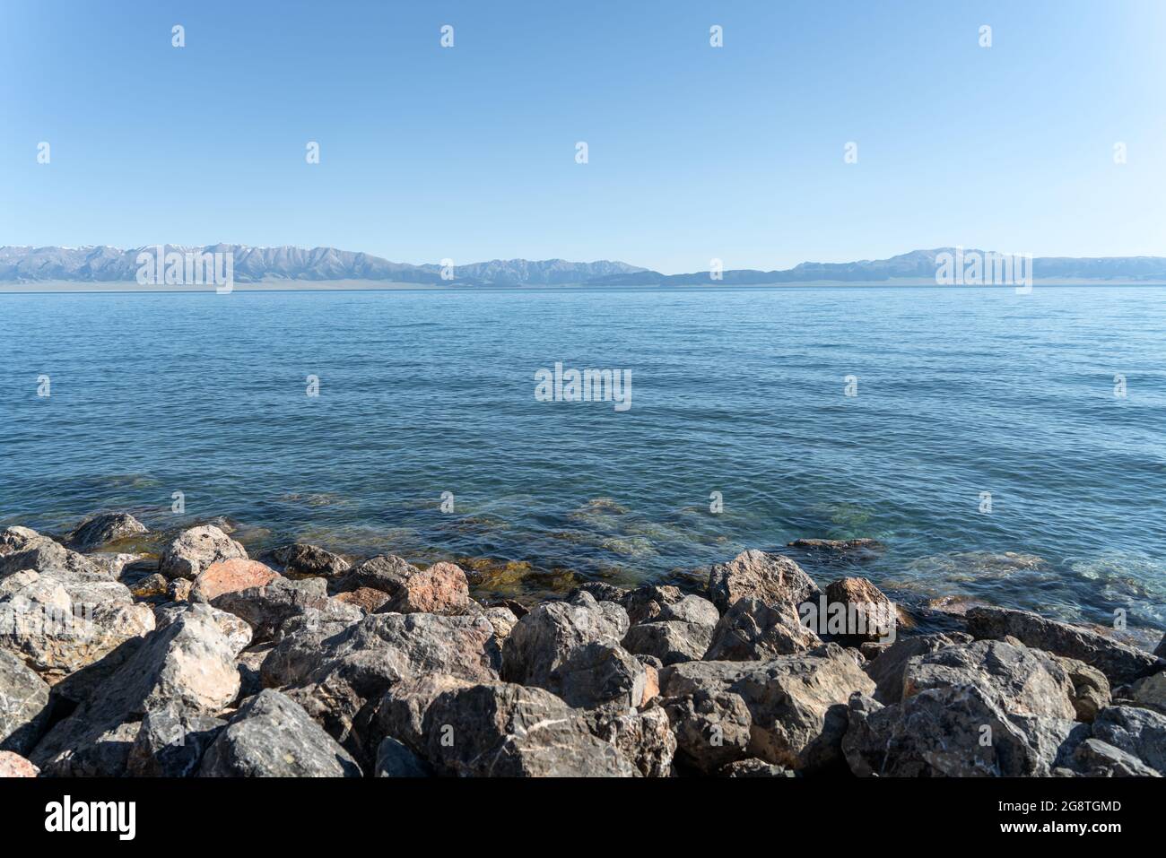 The calm surface of the lake and rocks. Shot in Sayram Lake, Xinjiang, China. Stock Photo