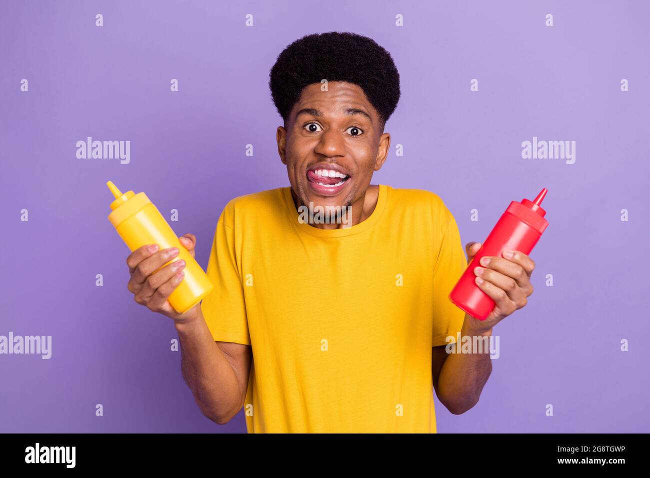 Portrait of attractive funky cheerful guy holding ketchup bottles