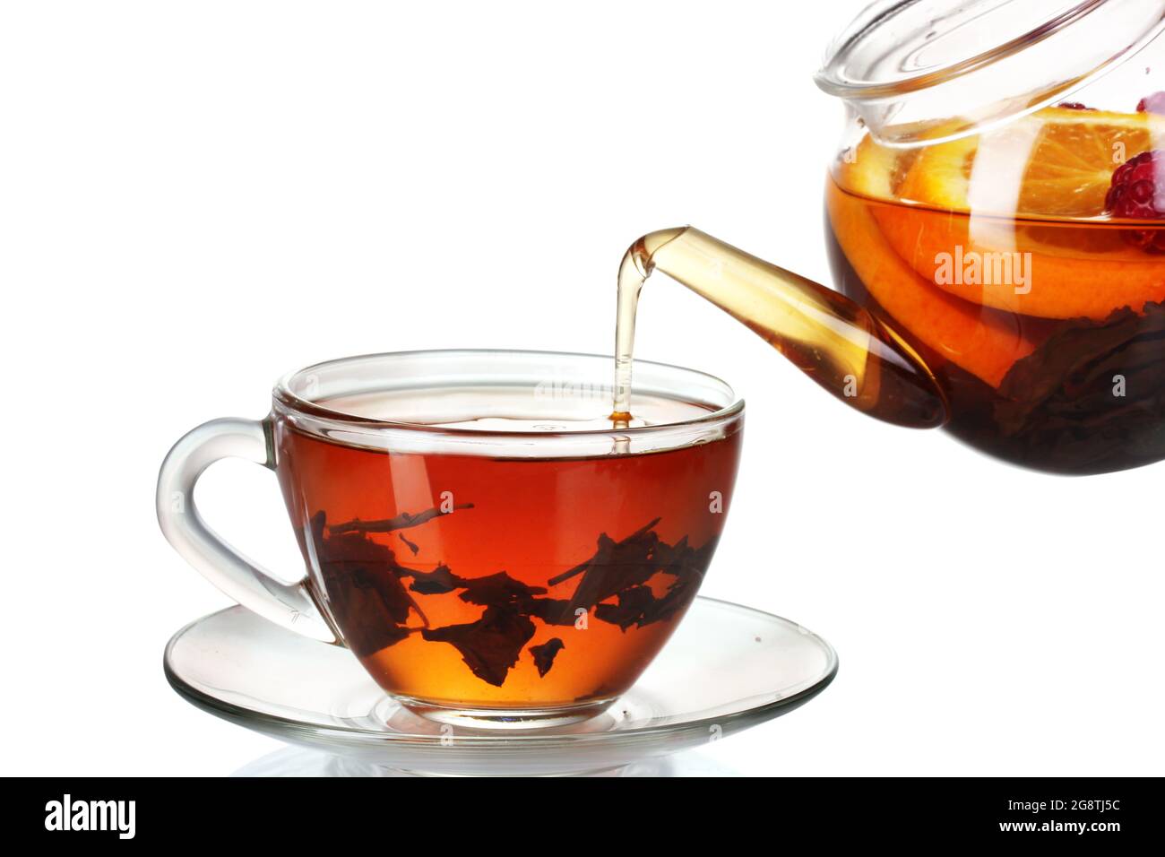 Glass teapot pouring black tea into cup isolated on white Stock Photo