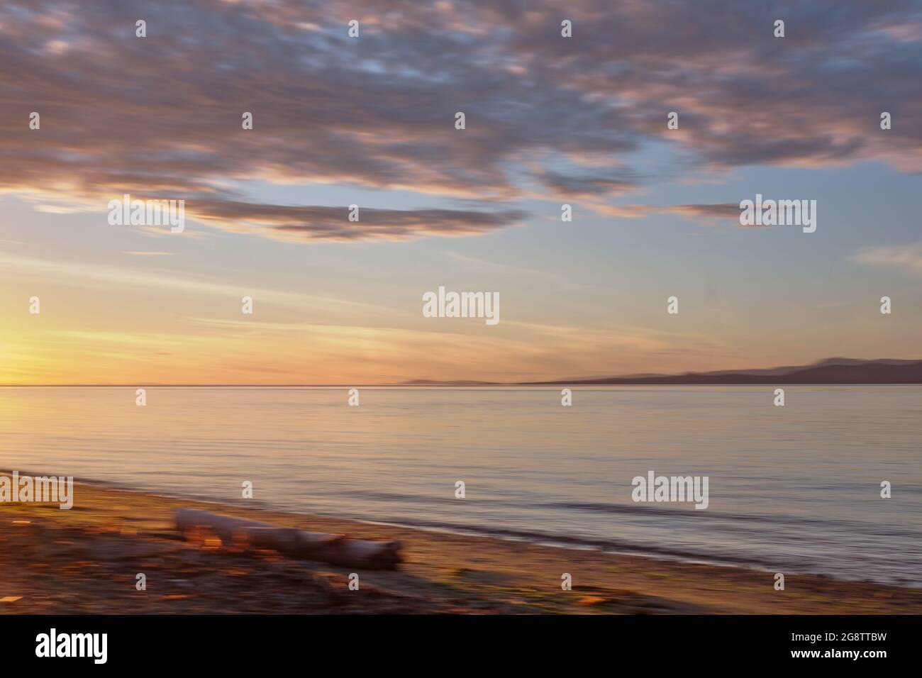 Horizontal panning (ICM) at Rathtrevor Provincial Park campground spreads golden light of sunset across beach, sea and distant islands.  Vancouver Is. Stock Photo