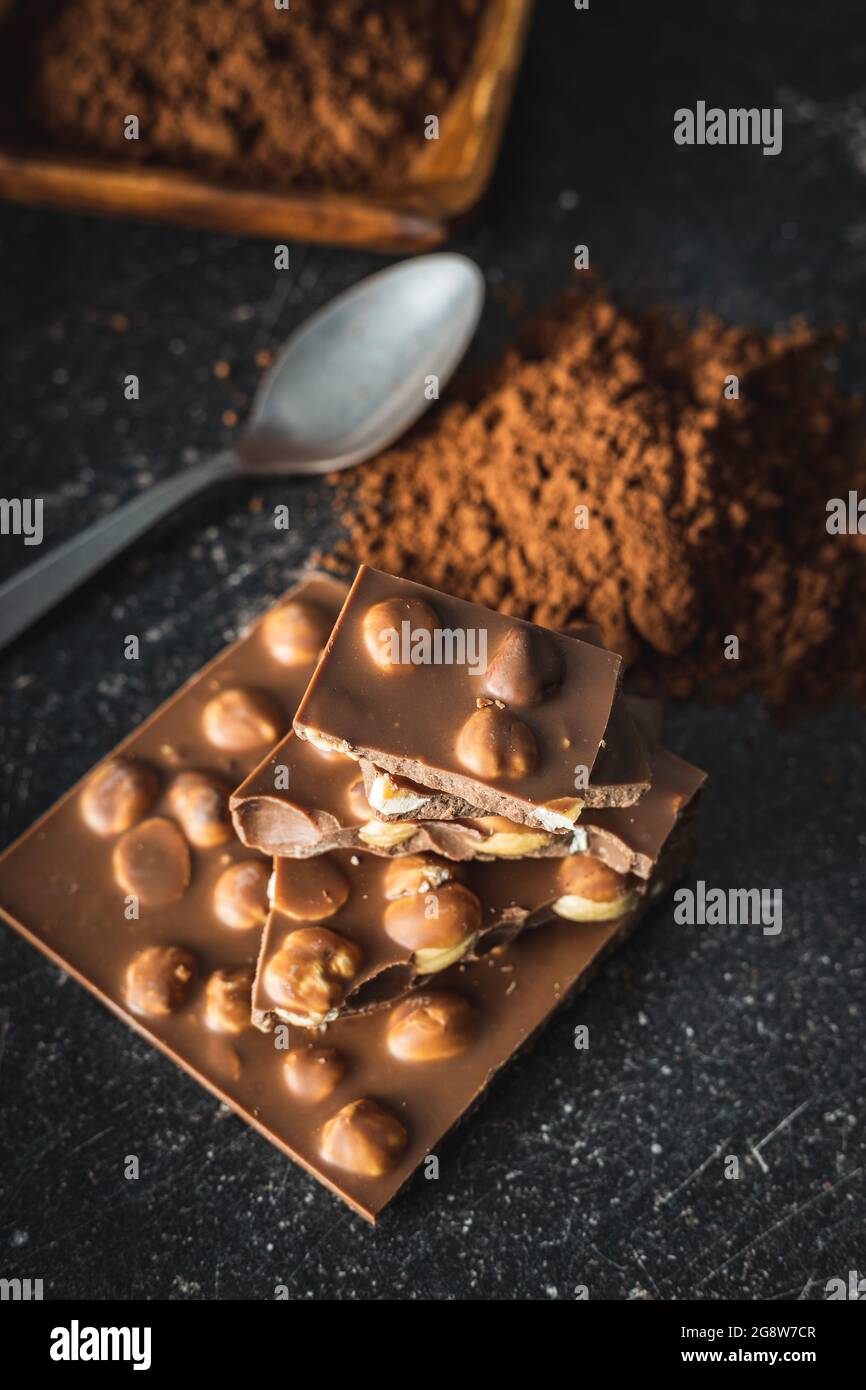 Nutty chocolate with hazelnuts and cocoa powder on black table. Stock Photo