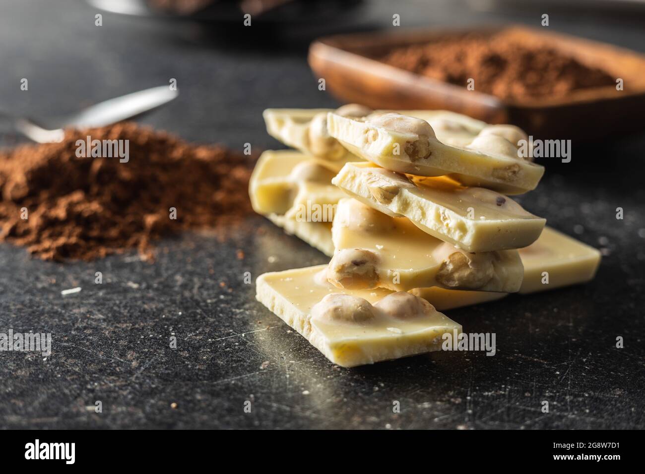 White nutty chocolate with hazelnuts on black table. Stock Photo