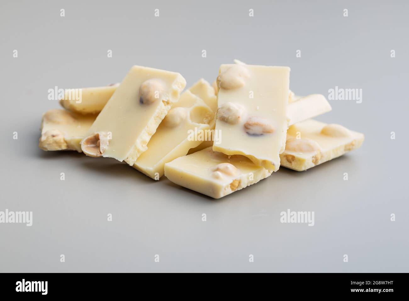 White nutty chocolate with hazelnuts on gray background. Stock Photo