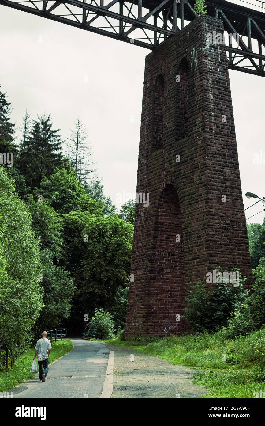 man walking under the old rail bridge, stone railway viaduct from below Stock Photo