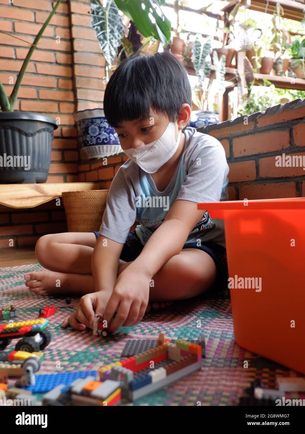 A boy with facemask play lego toys in his house. Stock Photo