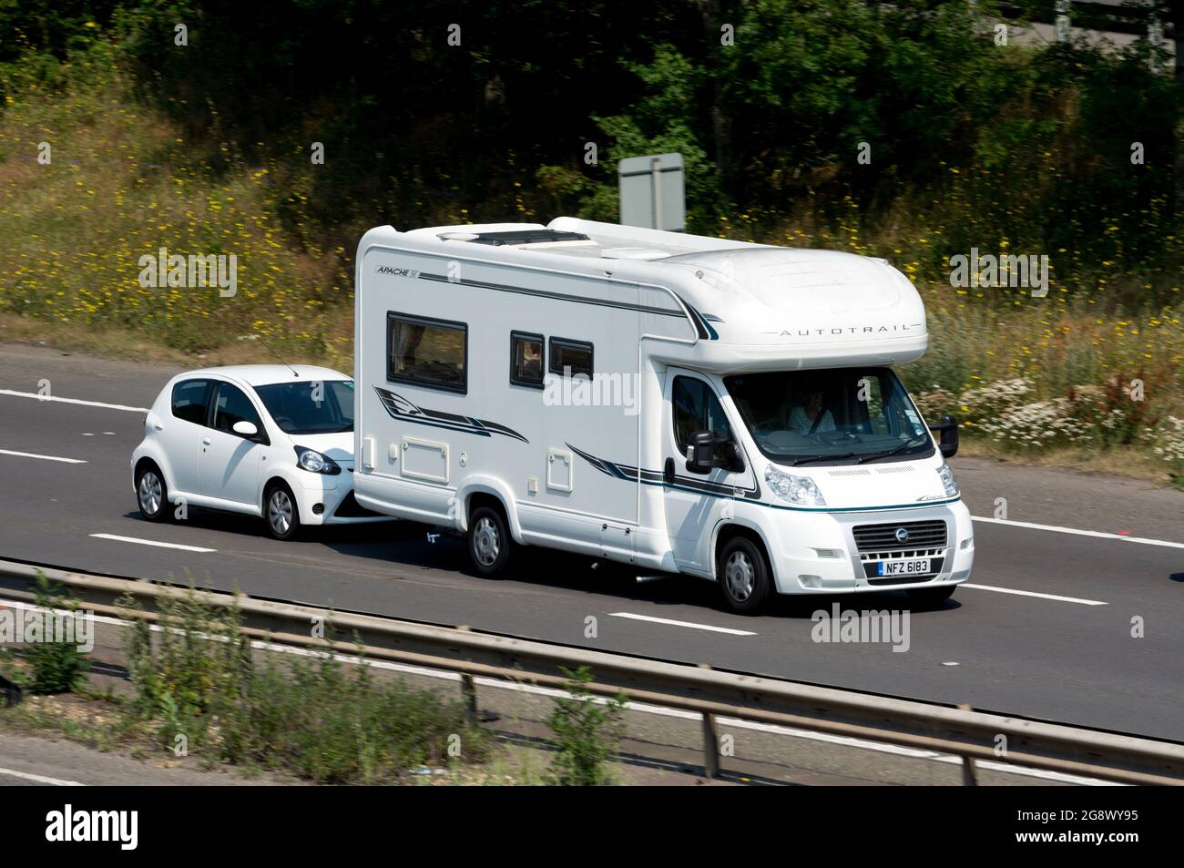 A motorhome towing a small car on the M40 motorway, Warwickshire, UK