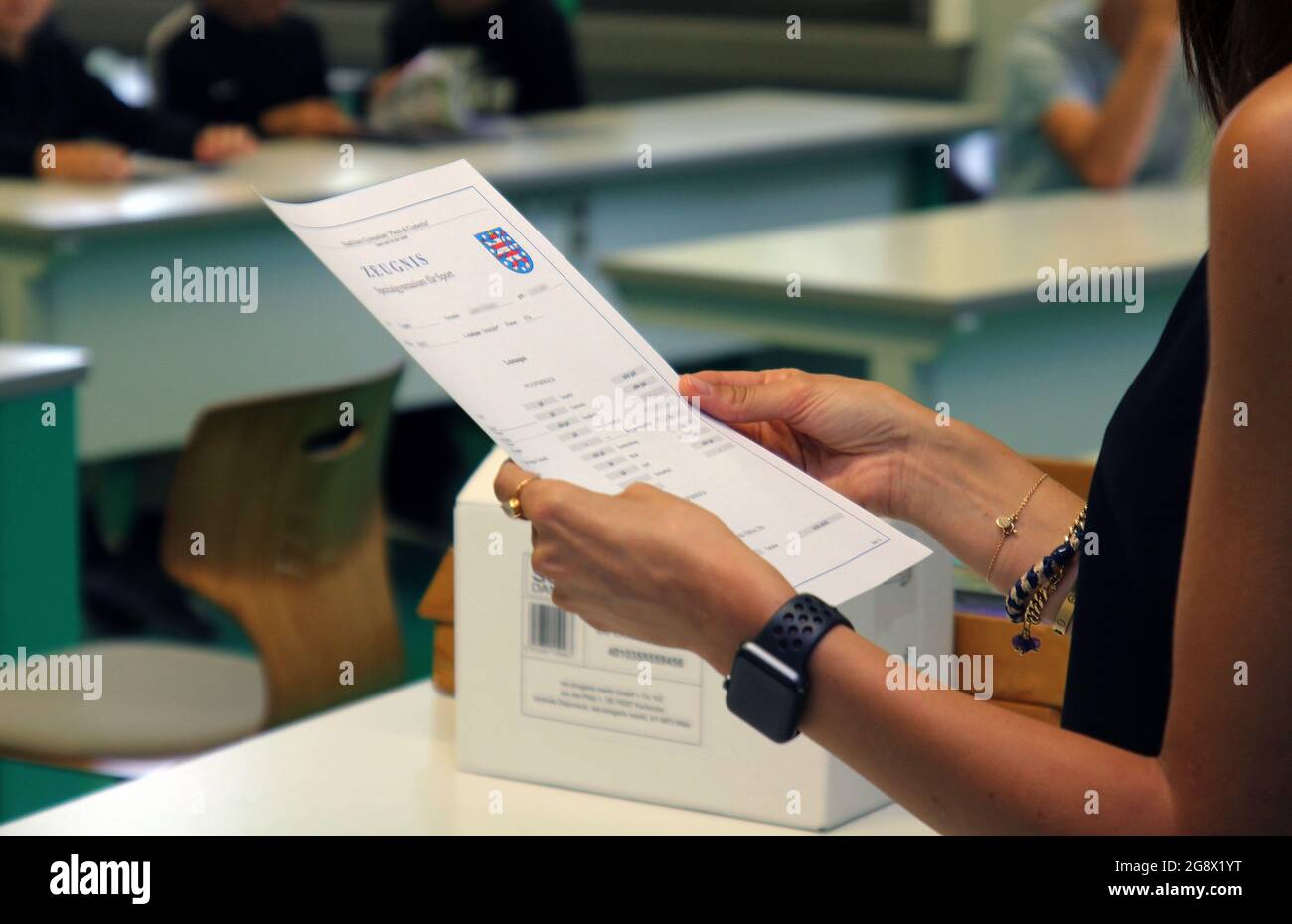 Erfurt, Germany. 23rd July, 2021. A teacher at a high school stands in a classroom on the last day of school before summer vacation, report card in hand. Credit: Martin Wichmann/dpa - ATTENTION: Names on certificates pixelated for legal reasons/dpa/Alamy Live News Stock Photo