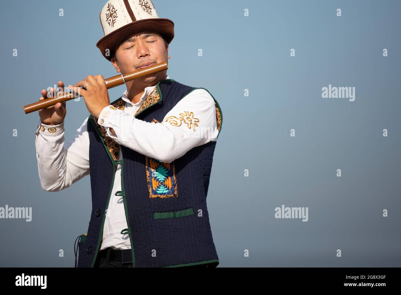 Kyrgyz musician playing traditional side blown musical instrument known as  Sybyzgy , in Issyk Kul, Kyrgyzstan Stock Photo