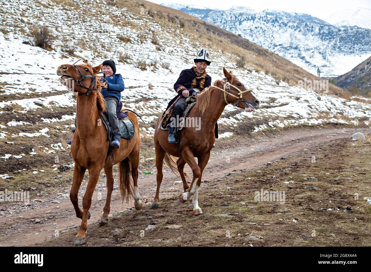Nomadic father and his son riding horse near Bishkek, Kyrgyzstan Stock Photo