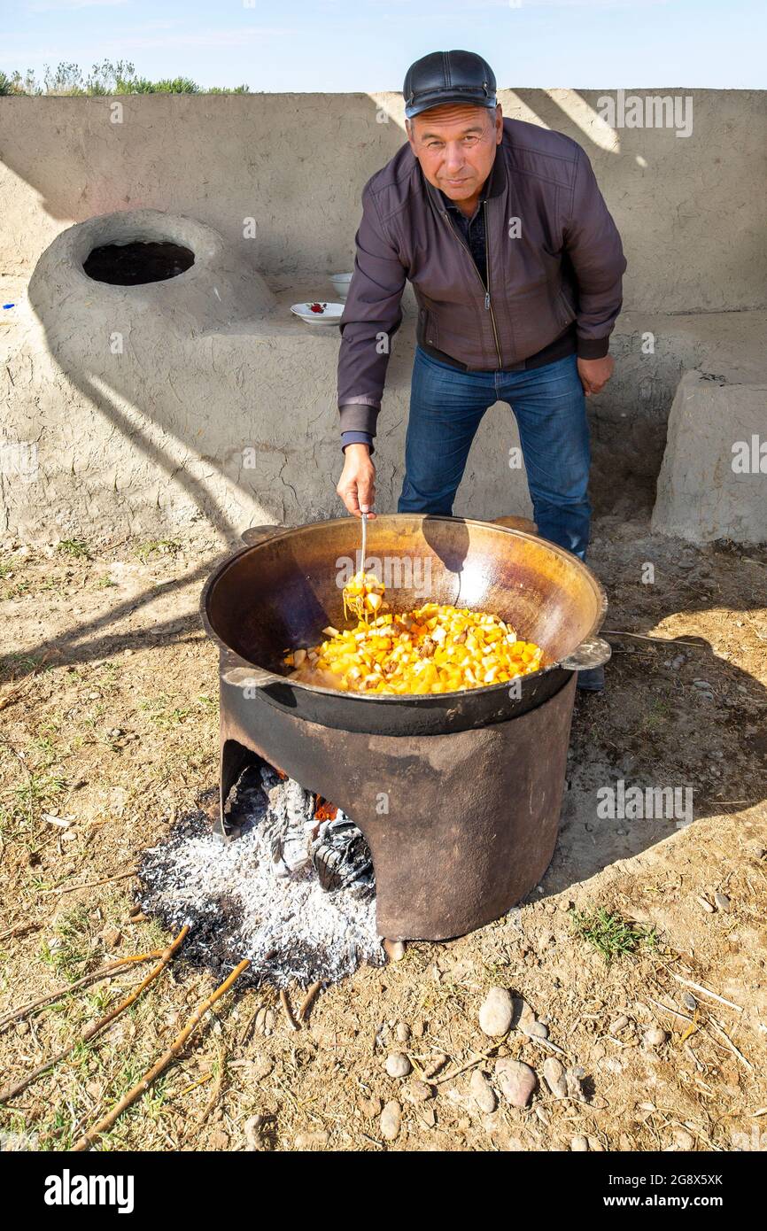 Uzbek man cooks vegetables in a big pot outdoors in the outskirts of Samarkand, Uzbekistan Stock Photo