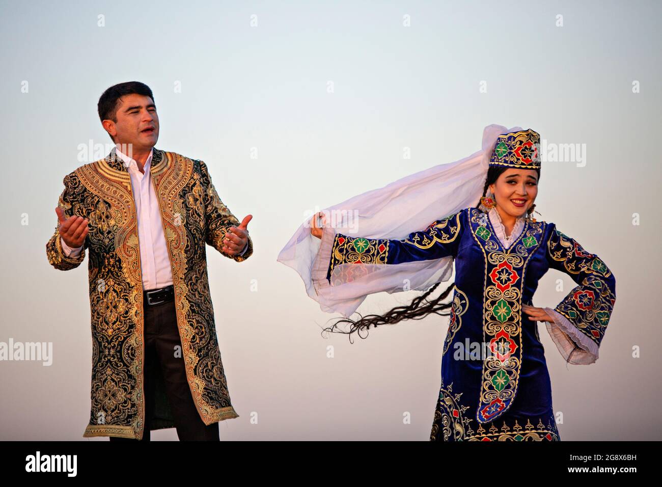Uzbek man and woman in national costumes dancing and singing in Bukhara, Uzbekistan Stock Photo