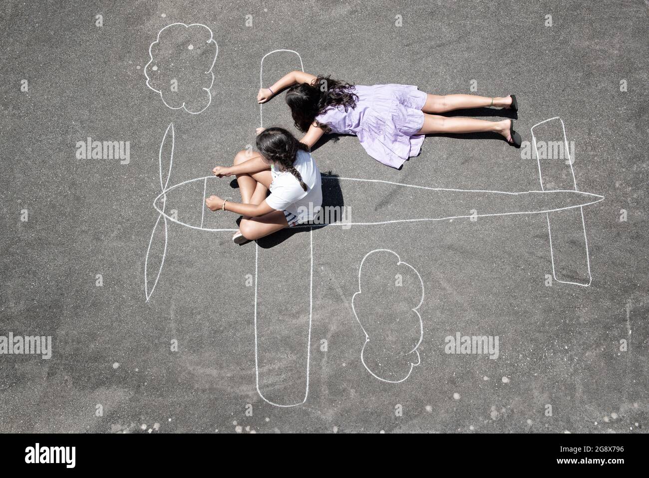 Young girls playing in the park with a chalk airplane Stock Photo