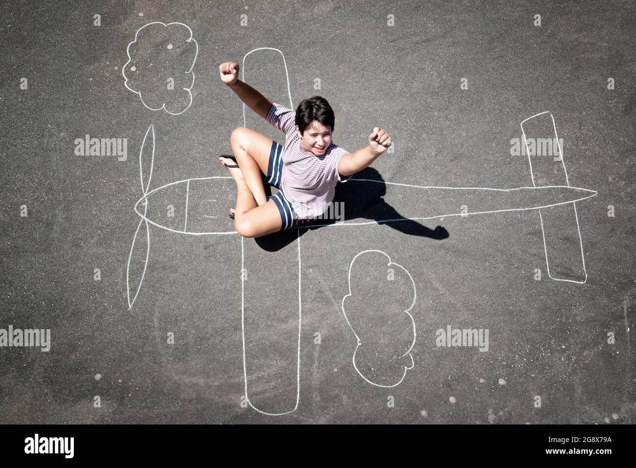 Young boy playing in a chalk drawn airplane Stock Photo
