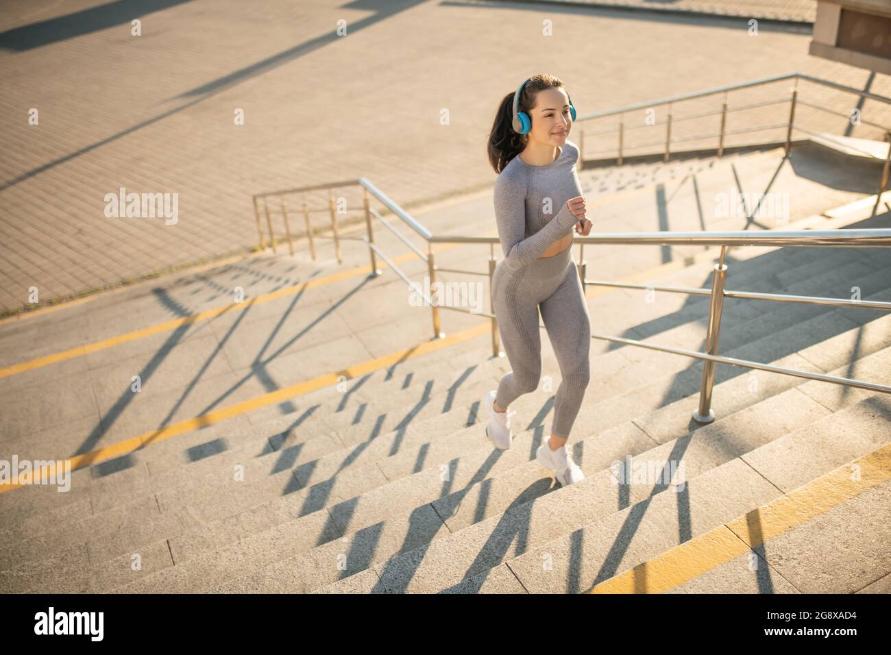 Sporty girl in grey sportswear having cardio on the stairs Stock Photo