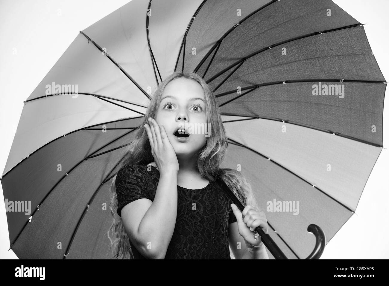 Feeling protected at this autumn day. Surprised childhood. School time. Small girl with umbrella in rainy weather. Happy little girl with umbrella Stock Photo