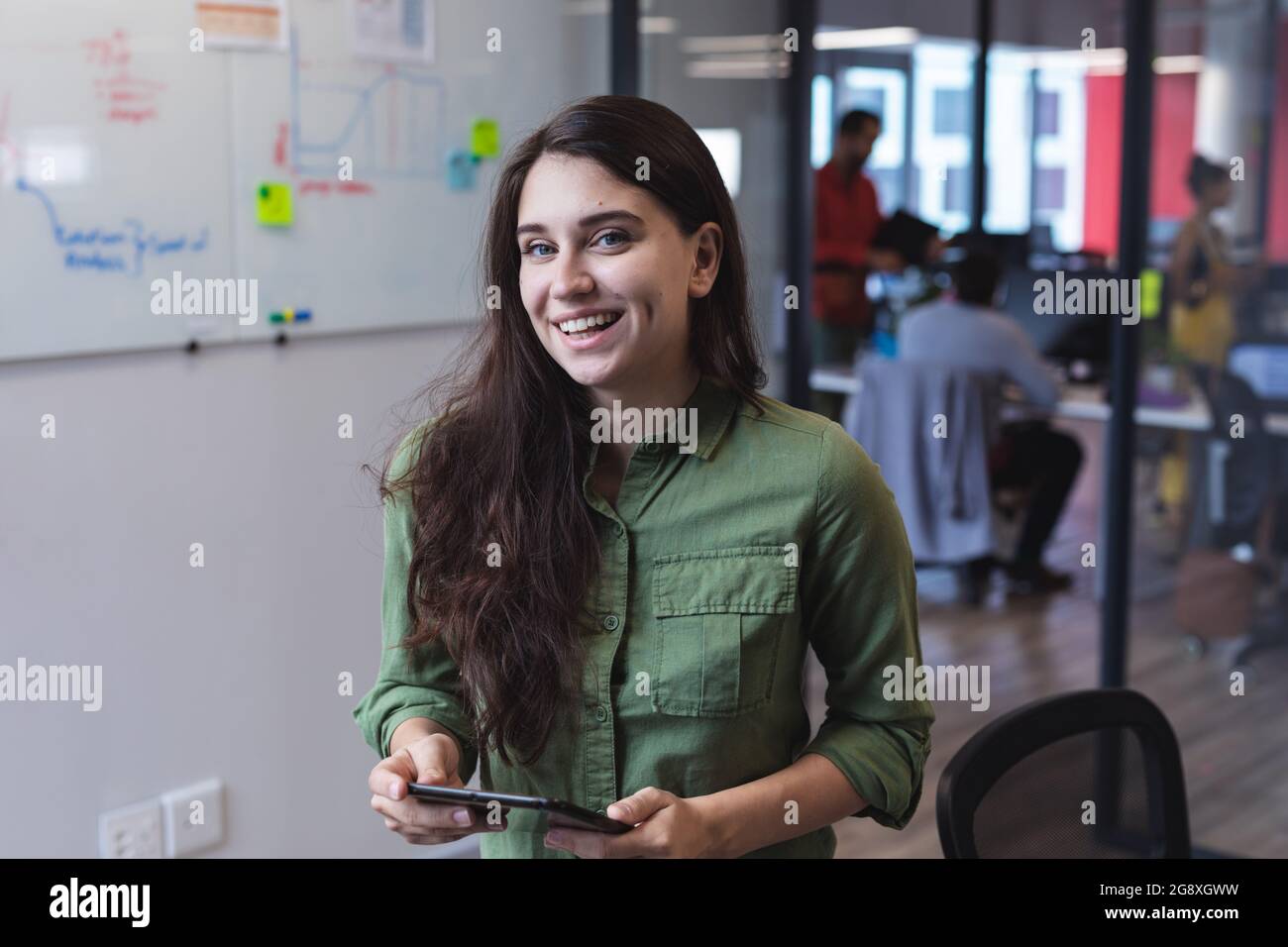 Portrait of caucasian female creative worker using tablet computer and looking at camera Stock Photo