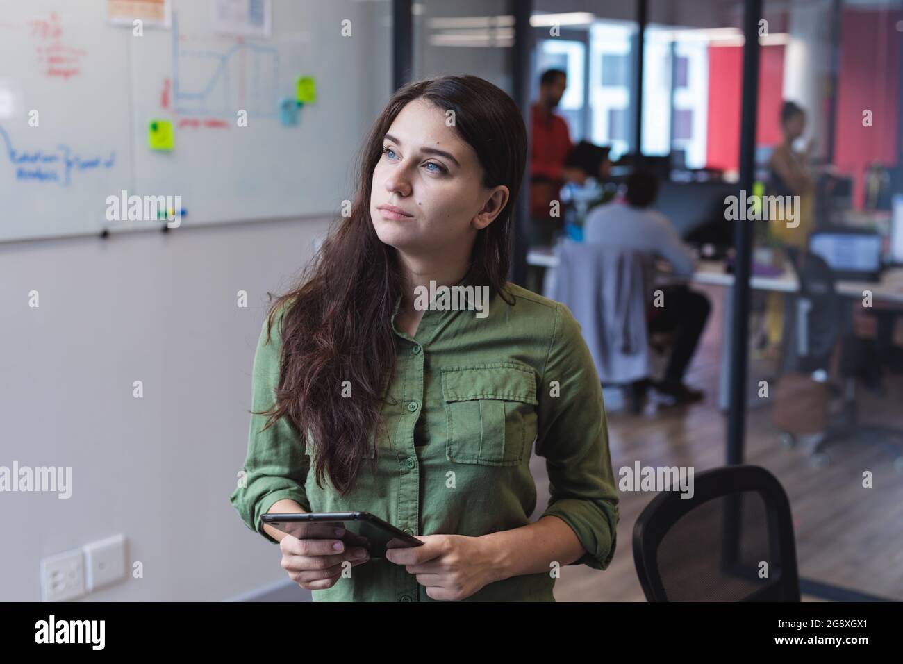 Caucasian female creative worker using tablet computer and looking away Stock Photo