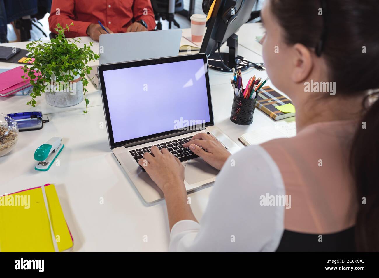 Caucasian female creative worker sitting at desk using laptop Stock Photo