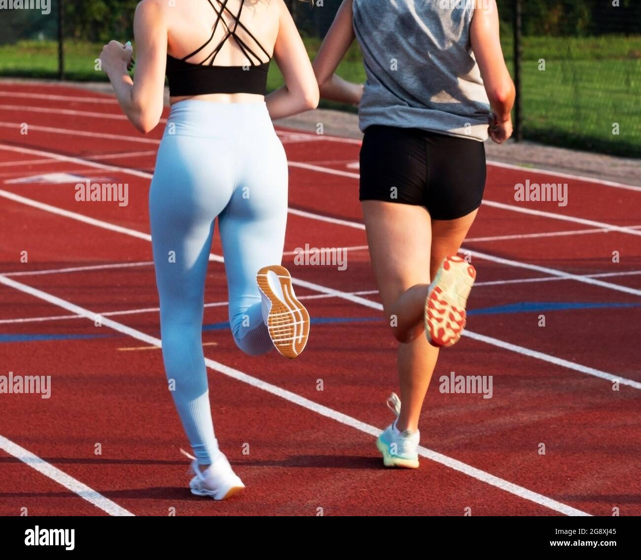 Rear view of two female college runners training together on a red