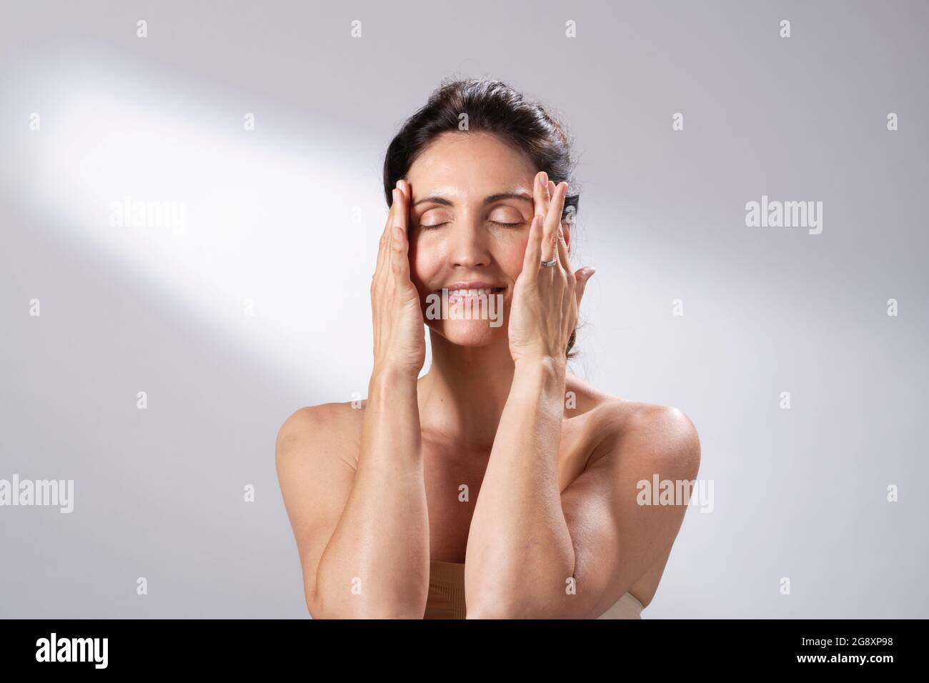 A woman's skincare regime. Hands and fingers on face and gently massage. Stock Photo