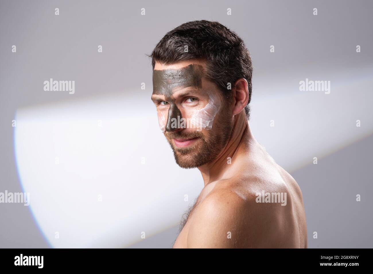 Man using facial products on his skin. Face mask treatments. Rejuvenating, moisture adding masks. Stock Photo
