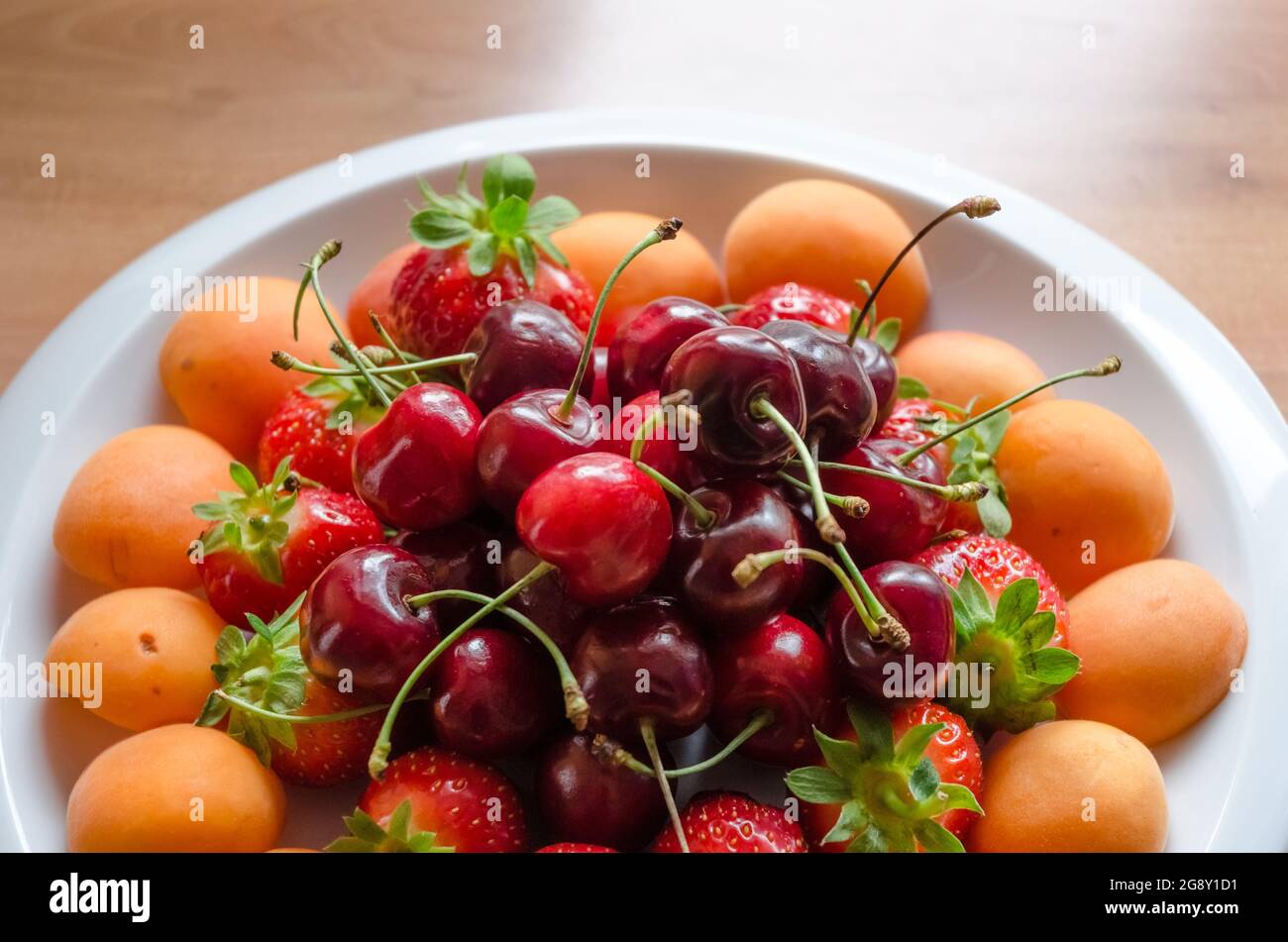 Friuts on a white plate with cherries, strawberries and mirabelle plums Stock Photo